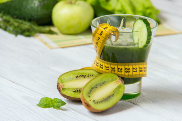 Healthy green smoothie with ingredients on white wooden background