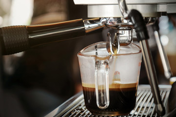 Fresh coffee in glass from professional coffee machine