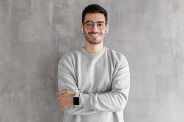 Wall Mural - Young handsome man standing with crossed arms against gray textured wall
