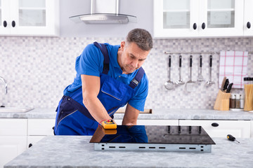 Wall Mural - mature repairman examining induction stove