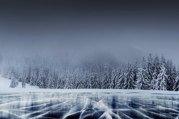 Wall Mural - Majestic winter landscape with cracks on the surface of the blue ice. Frozen lake in winter mountains. A dramatic scene with low black clouds, a calm before the storm