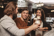 Group of happy friends clinking their beer glasses, laughing joyfully, celebrating at the irish pub. Bearded man screaming excitedly, toasting with his friends at the bar. Oktoberfest, party concept