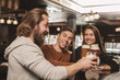 Group of happy friends clinking their beer glasses, laughing joyfully, celebrating at the irish pub. Bearded man screaming excitedly, toasting with his friends at the bar. Oktoberfest, party concept