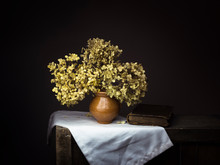 Dramatic Chiaroscuro Style Photo Of Dried Hydrangea Flowers With Old Book On Dark Background. Melancholy Still Life With Copy Space.