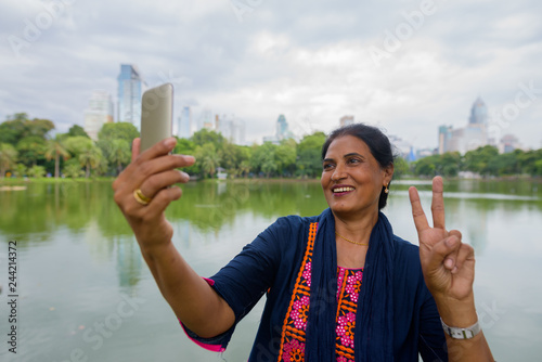 Foto Mature beautiful Indian woman taking selfie with mobile phone