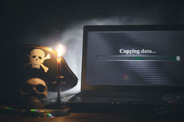 illegal data copying concept. cybercrime. computer piracy background. pirate hat, human skull, lapto