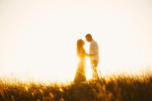 Portrait Of Handsome Kissing Couple On Sunset Or Sunrise In Meadow