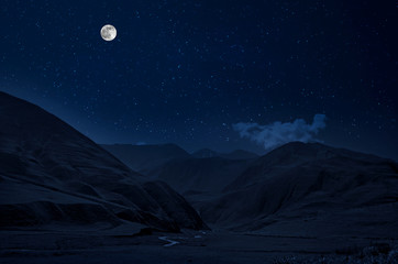 Wall Mural - mountain road through the forest on a full moon night. scenic night landscape of dark blue sky with 