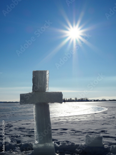 Fotografía large ice cross near the hole on the background of blue sky and endless frozen river