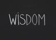 Word wisdom written on black chalkboard, copy space