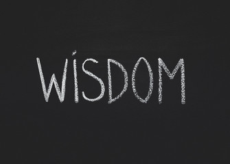 word wisdom written on black chalkboard, copy space