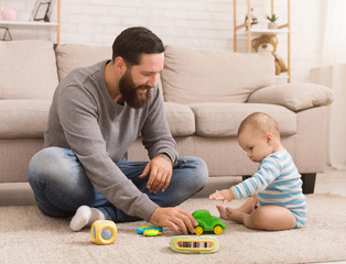 Young father and his baby boy playing with toy car