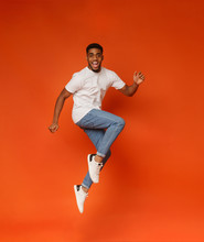 Excited African-american Man Jumping On Orange Background