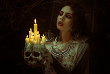 Candles In Skull, Vampire, Demonic Woman Dressed In White Lace And Silver Jewelry. Has Fangs And Thick Brown Hair
