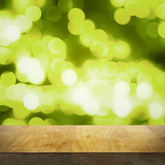 Wall Mural - Empty wooden top table and bright blurred green background with lights and bokeh, focus on the tabletop