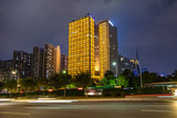 Fototapeta  - Beautiful street at night with light trails in Guangzhou central business district. Image of blur motion of cars on the city road.