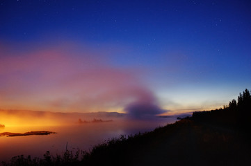 Wall Mural - mist over river under starry sky. mist illuminated by the gas-discharge lamps.