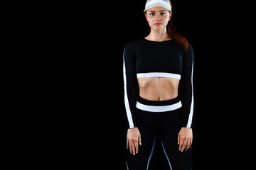 Wall Mural - Strong athletic woman , posing on black background wearing in sportswear. Energy fitness and sport motivation. Copy space.