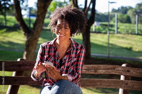 Fotografie, Obraz Portrait of a young african american woman listening to music on cell phone - Im