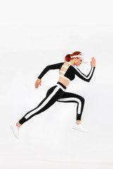 Wall Mural - Strong athletic woman sprinter, running on white background wearing sportswears. Fitness and sport motivation. Runner concept with copy space.