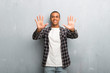 © luismolinero - Young african american man with checkered shirt counting ten with fingers