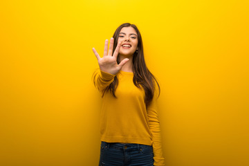 Wall Mural - Teenager girl on vibrant yellow background counting five with fingers