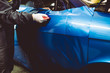 © hedgehog94 - Car wrapping specialist putting vinyl foil or film on car. Selective focus.