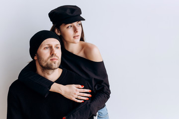 Wall Mural - Two hipster models: a man and a woman in a blank black t-shirt, jeans and posing. in a black hat, cap, love, kisses