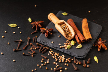 Wall Mural - Exotic herbal Food concept Mix of the organic Spices cinnamon stick, cardamom pods, star anise and coriander seeds on a black slate stone plate with copy