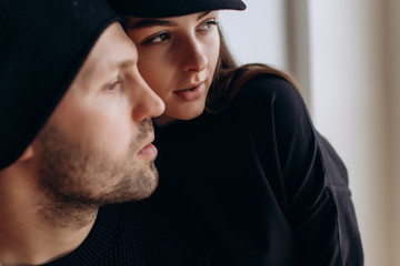 Wall Mural - Two hipster models: a man and a woman in a blank black t-shirt, jeans and posing. in a black hat, cap, love, kisses