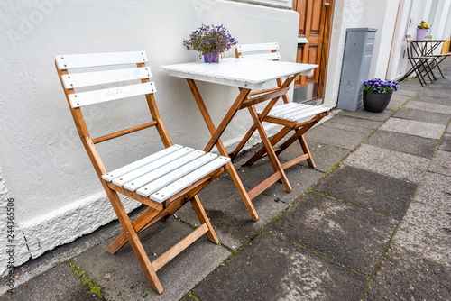 Foto White empty wooden table outside restaurant cafe with two chairs on sidewalk str