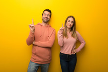 Group Of Two People On Yellow Background Showing And Lifting A Finger In Sign Of The Best