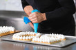 © herraez - Close up view, hands of the chef with confectionery bag cream preparing a fiftie years old birthday cake at pastry shop kitchen .