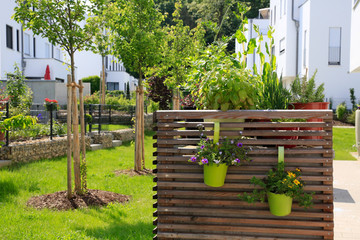 Sticker - Moderner Gartenbau: Mit Holzwänden verkleidete Mülltonnen vor frisch gepflanzten Obstbäumen 