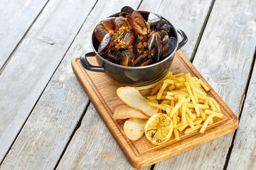 Belgian mussels in white wine with tomatoes, croutons and French fries. Fried food, pile of shell mussels, potato and croutons.