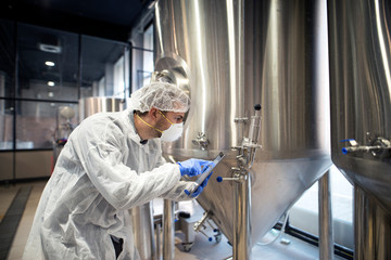 Professional technologist checking production in factory. Industrial worker with tablet in production plant.