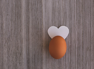 One Organic Brown Chicken egg  Decorated  White Heart like Ears on a Wooden Table. Copy Space. Easter Concept.