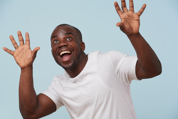 Handsome black man looking at camera and smiling, against pale blue background.