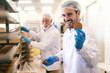 © Dusan Petkovic - Young smiling Caucasian worker showing cookie while standing in food factory.