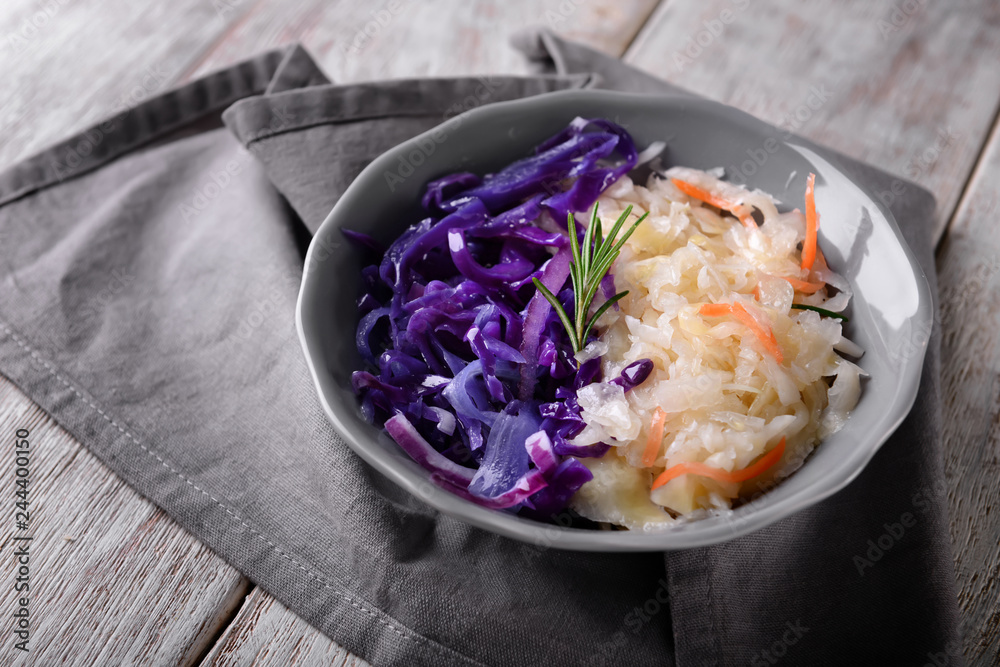 Bowl with tasty fermented cabbage on wooden table