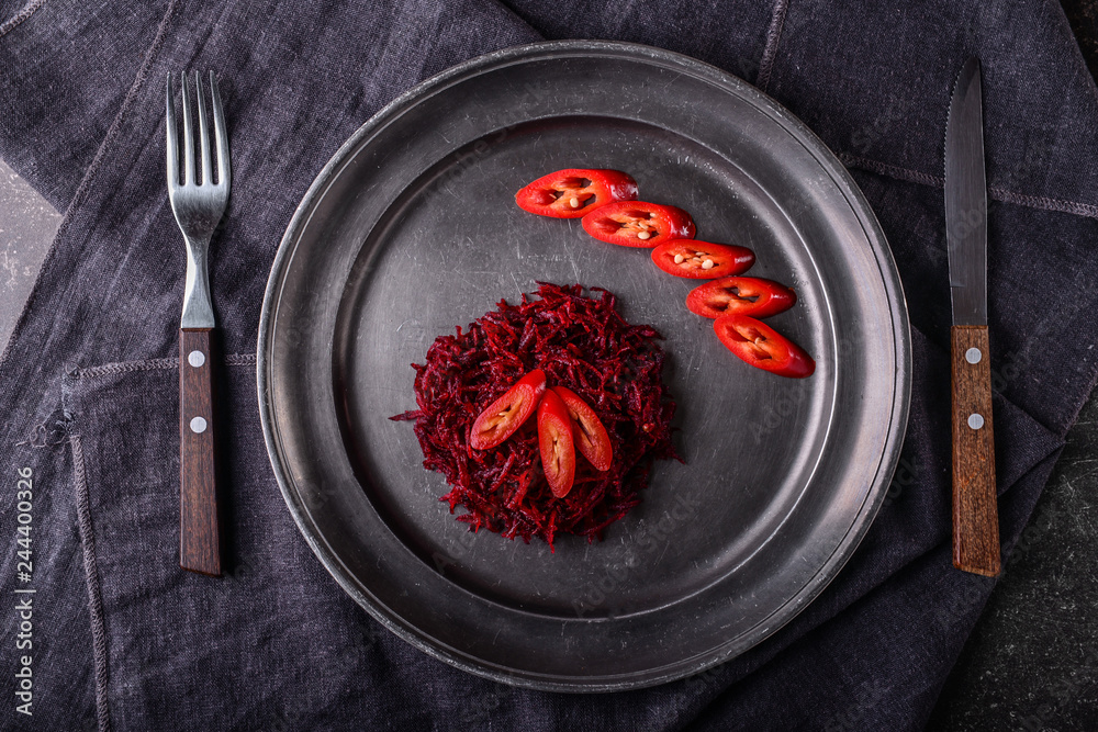 Plate with tasty fermented beetroot and cut chili pepper on table