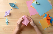 Young Woman Making Origami On Wooden Table