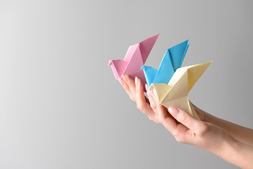 Wall Mural - Female hands with origami birds on light background