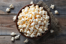 A Wooden Bowl Of Salted Popcorn At The Old Wooden Table. Top View. Flat Lay. Dark Background