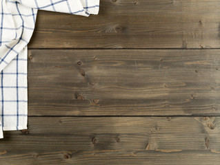 Blue and white checkered dishcloth on brown rustic wooden plank table flat lay top view from above