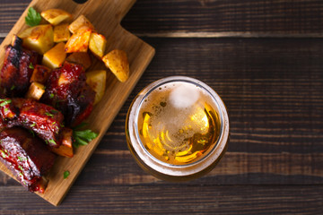 Wall Mural - Glass of beer and grilled pork spare ribs with fry, tasty snack to beer. Beer and food concept. Ale and meat. View from above, top studio shot