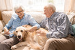 Portrait of happy senior couple with dog sitting on couch enjoying family weekend at home in retirement