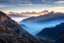 Mountains In Fog At Beautiful Sunset In Autumn In Dolomites, Italy. Landscape With Alpine Mountain Valley, Low Clouds, Trees On Hills, Village In Fog, Blue Sky With Clouds. Aerial View. Passo Giau