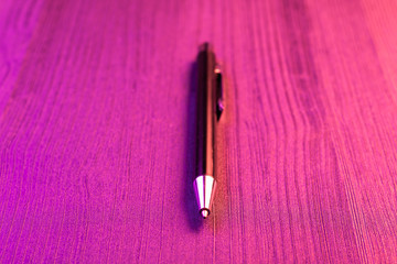 Wall Mural - Elegant pen on wood background and pink light. Business black pen.