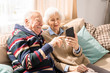 © Seventyfour - Portrait of adorable senior couple using smartphone together video chatting with family at home, copy space